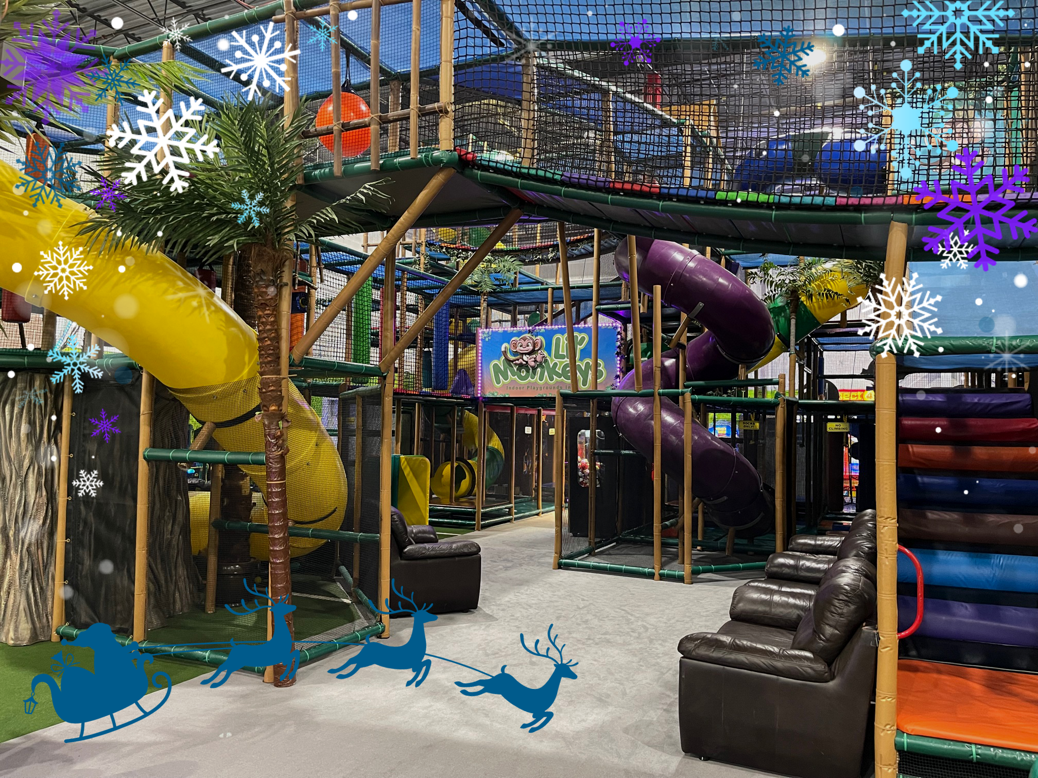 Large indoor playground structure featuring colorful tunnels, slides, climbing areas, and playful palm tree decorations, creating an adventurous and fun atmosphere for children
